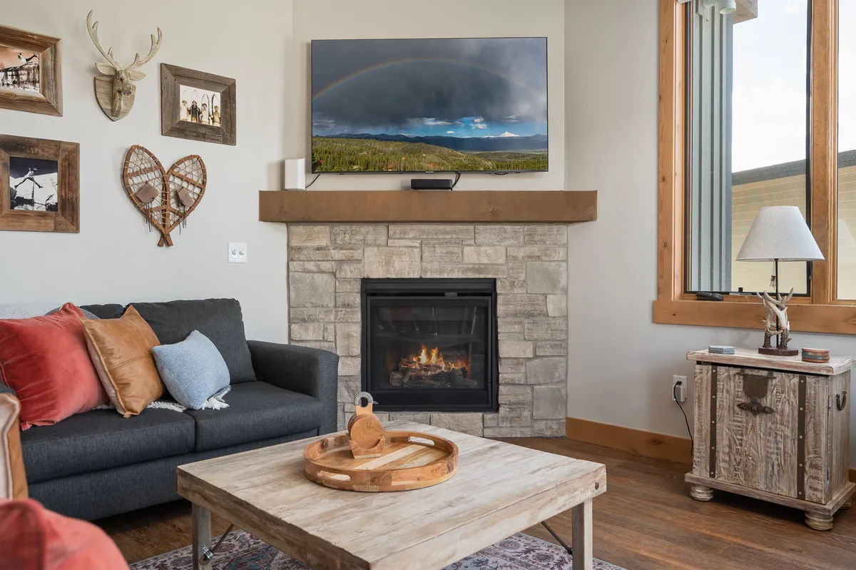 A comfortable living space centered on a fireplace, with a large, cushy sofa inviting guests to relax. A television is prominently featured above the fireplace, creating an ideal spot for movie nights or spirited gaming sessions. The warm lighting and thoughtful layout make this a perfect setting for group entertainment and family bonding.