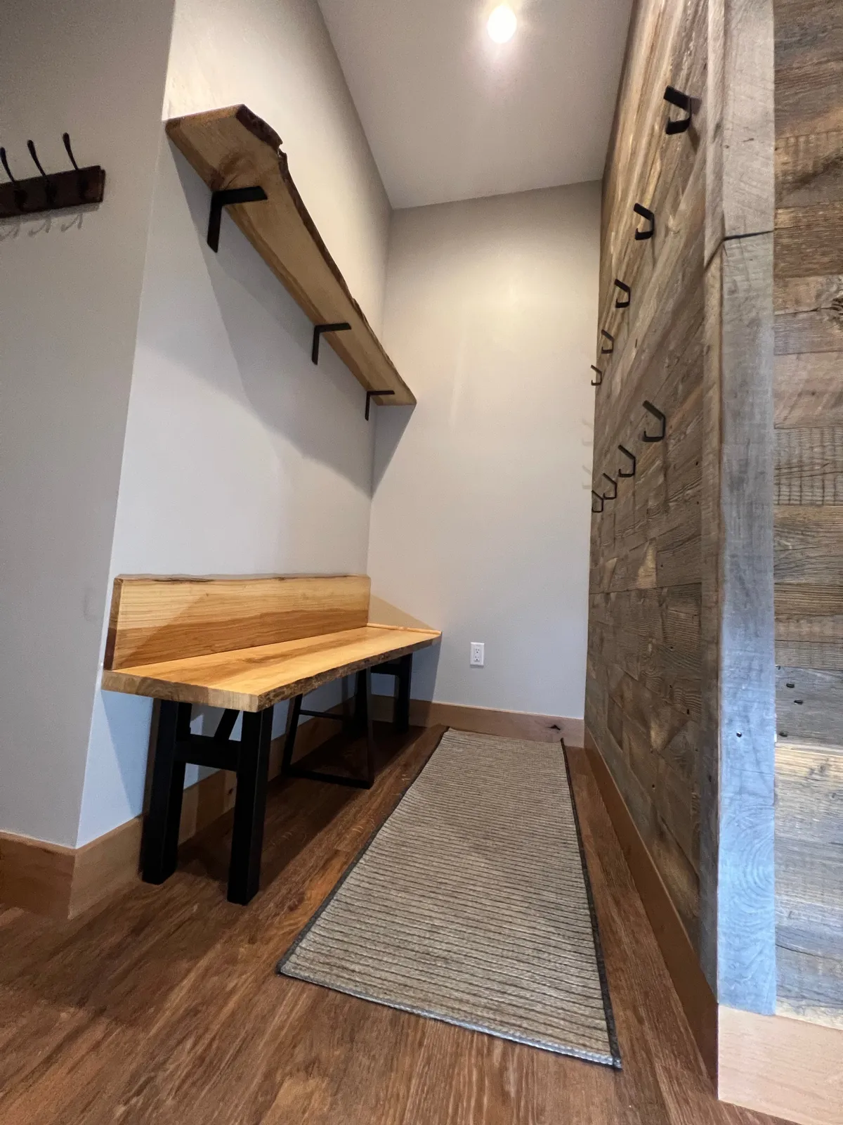 An inviting mudroom area with a wooden bench, storage shelves, and a textured wall, designed for guests to take off shoes and store outdoor gear. The space is functional and welcoming, hinting at the active lifestyle available just beyond the door.
