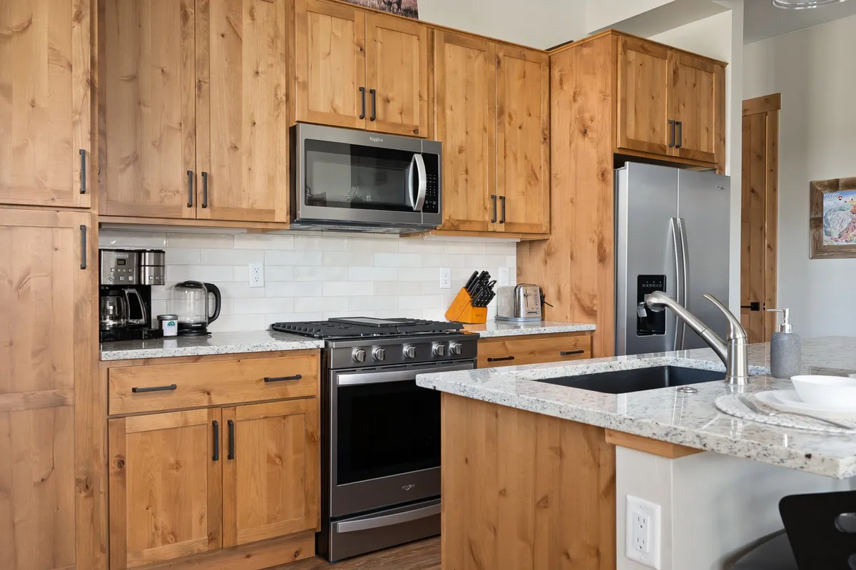 A kitchen with wood cabinetry, granite countertops, stainless steel appliances, and a central island—ideal for hosting, cooking, and gathering with family or friends.