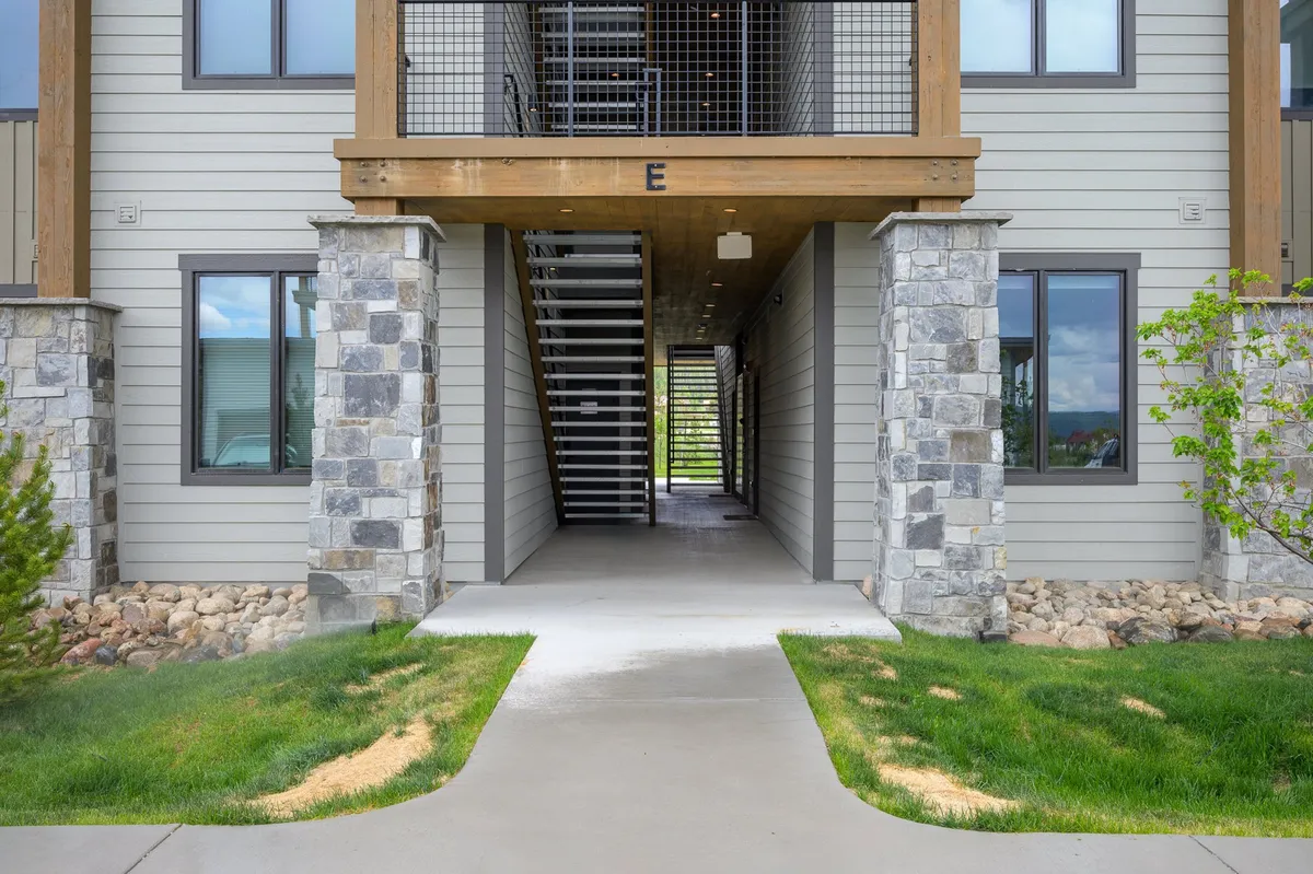 This image captures the inviting exterior of the home, featuring stone pillars, a welcoming staircase, and a pathway bordered by green grass. The scene suggests accessibility and a friendly entrance, ideal for families arriving with young children and strollers.